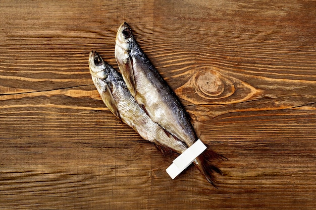 Due pesci sciabola essiccati all'aria salati con etichette di carta sulle code su fondo di legno