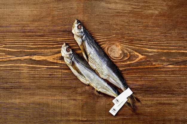 Two salted sundried sabrefish with paper labels on tails on wooden surface