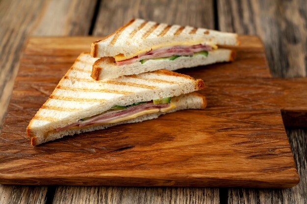 Two sandwiches on a cutting board on a wooden background in a rustic style.