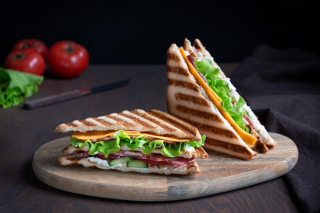 Photo two sandwiches made of slice of meat and cheese tomatoes between toasted bread on wooden table