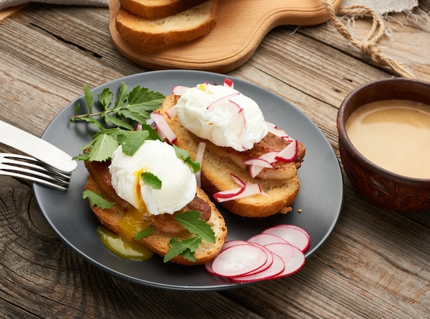 Photo two sandwiches on a toasted white slice of bread with poached eggs, green leaves of arugula and radish