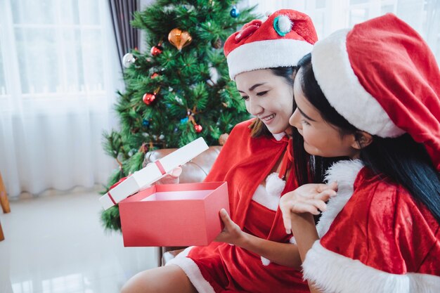 두 명의 산타 섹시한 여성이 크리스마스 축제에 집에서 행복한 미소와 함께 선물 상자를 엽니다.