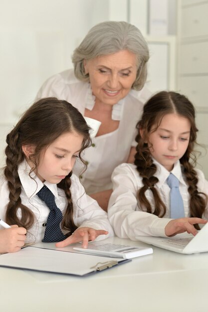 Two School aged girls making homework with granny