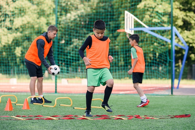 Two school boys are running ladder drills on during football summer camp.