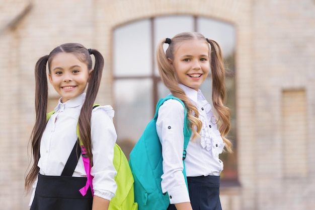 Two school girls best friends smile together outdoor