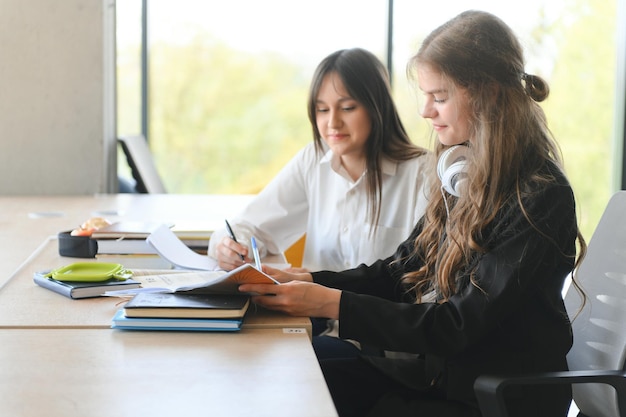 2 人の女子学生の友人が一緒に勉強します彼らは机に座ってタスクを実行します