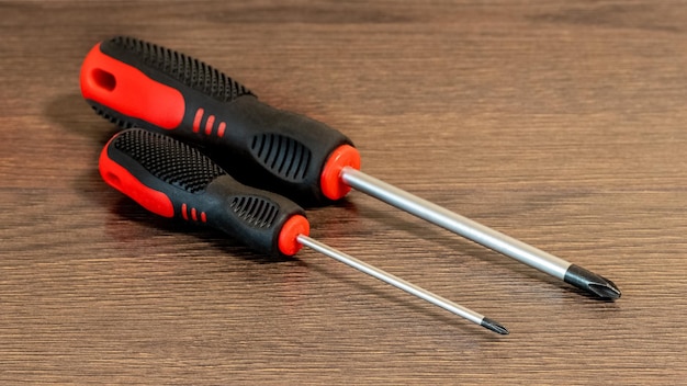 Photo two screwdrivers of different sizes on a wooden table