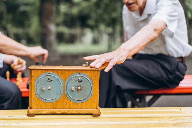 Two senior adult men playing chess on the bench outdoors in the park.