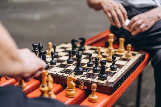 Two senior men playing chess on the bench outdoors in the park