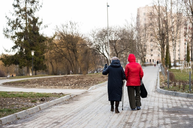 Two senior woman walking in an park Back view happy old friends