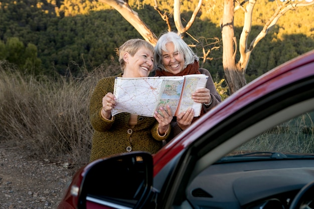 Foto due donne anziane che consultano una mappa mentre sono fuori per un viaggio nella natura