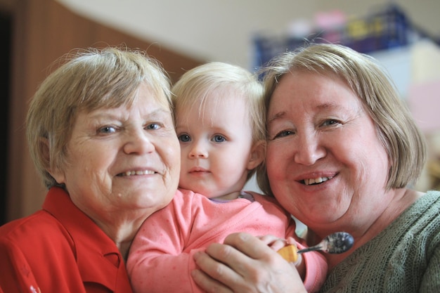 Two senior women - grandmothers with baby girl todler, close up