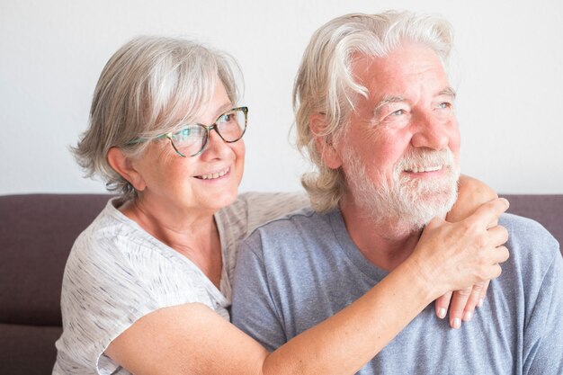 두 노인과 성숙한 부부는 집에서 소파에 앉아 사랑과 애정으로 행복한 카메라를 바라보며 포옹했다