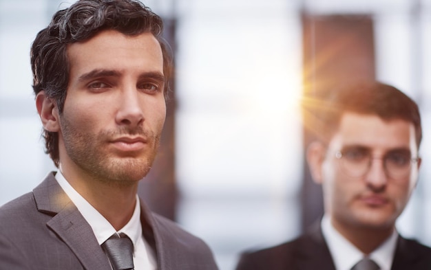 Two serious young businessmen standing with arms crossed in office