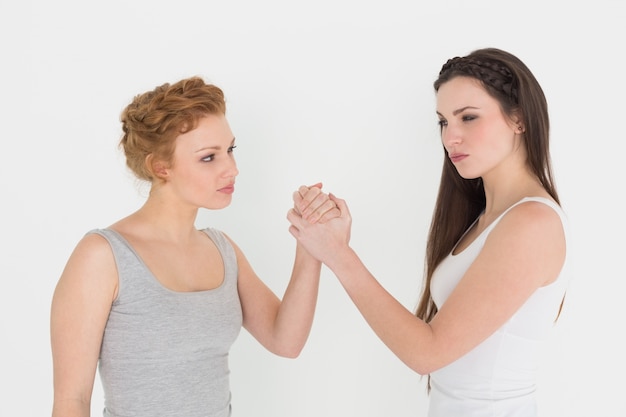 Two serious young female friends arm wrestling