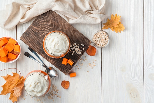 Two servings of pumpkin parfait with cereals on a light background Autumn healthy dessert
