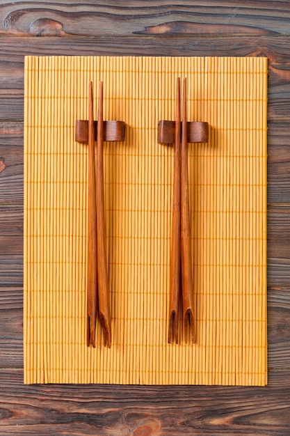 Two sets of sushi chopsticks on wooden bamboo background, top view.