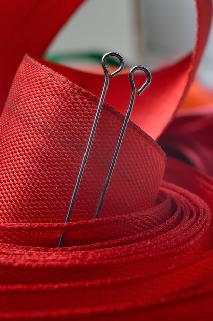 Two sewing pins on the background of a red cloth tape. close-up.