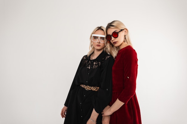 Two sexy fashionable young girl with fashionable sunglasses wearing a vintage dress