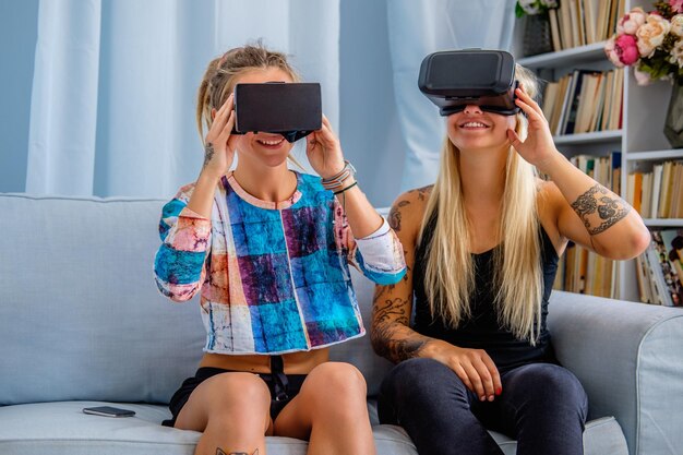 Two sexy females having fun with virtual reality glasses device at home.