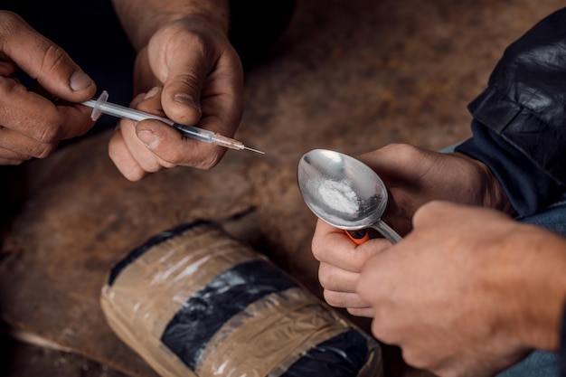 Фото Двое потрепанных мужчин готовят инъекции наркотиков в трущобах
