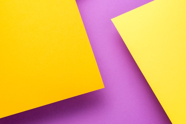 Two sheets of yellow and orange paper soar above the purple background