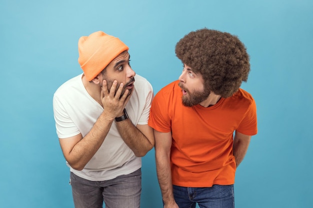 Two shocked men standing looking at each other with big eyes and open mouth being surprised