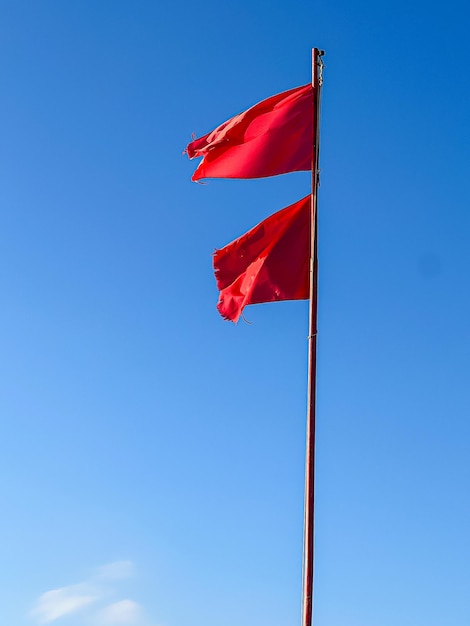 Photo two signal red flags raised on the beach to warn of a storm at sea