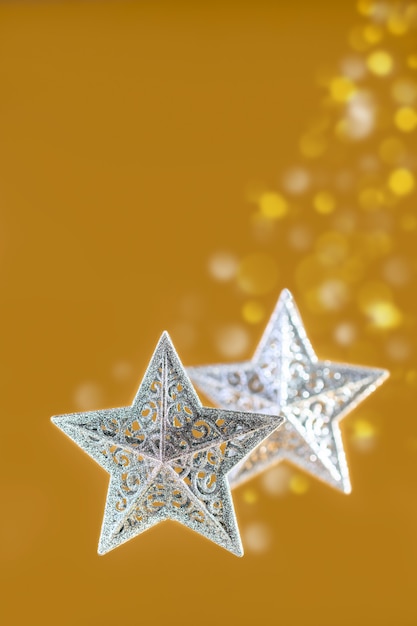 Two silver Christmas stars with a Golden background of blurry lights