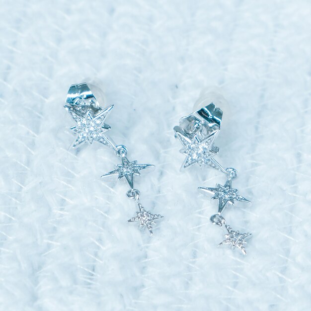 two silver snowflakes are on a white blanket.