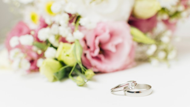 Photo two silver wedding rings near the flower bouquet