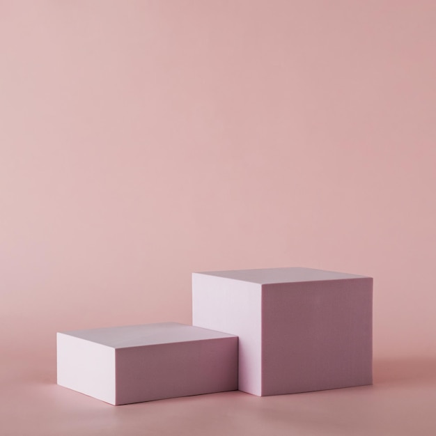 Две простые прямоугольные формы разного размера с тенями, помещенные на простой розоватый фон с копией пространства.
