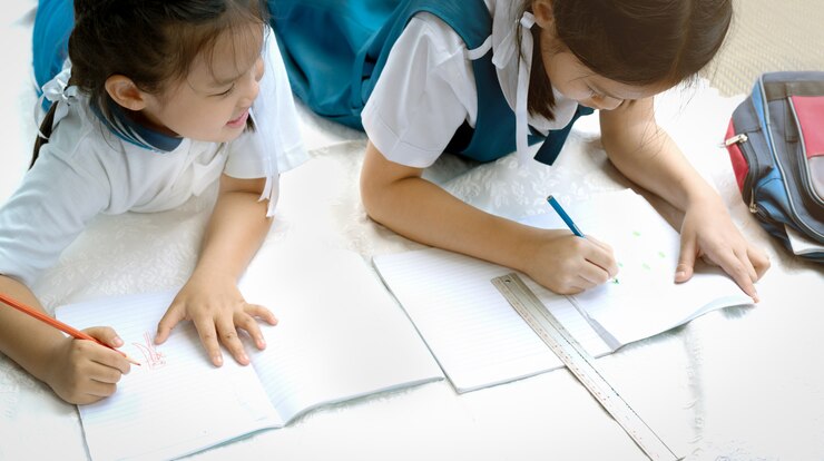 Photo 두 자매 소녀는 그림 그리기 수업 소녀의 책 결정을 씁니다