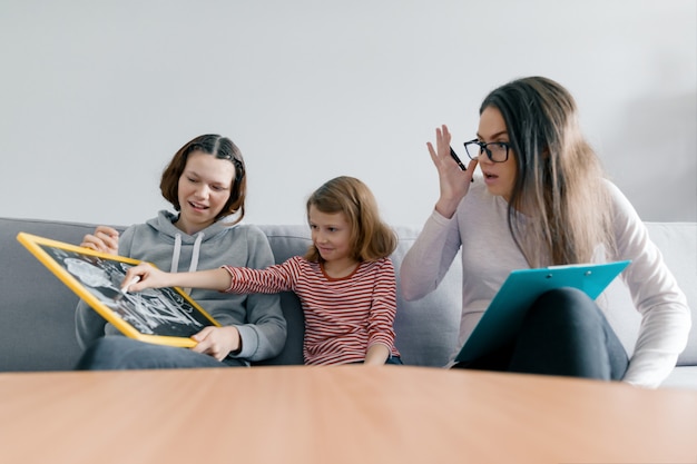 Two sister girls talking with young woman family psychologist