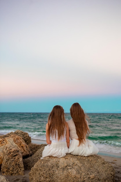 2 人の姉妹がビーチで夕日を楽しむ