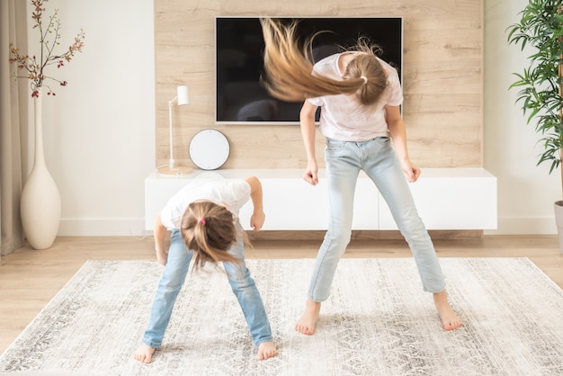 Two sisters having fun dancing in living room