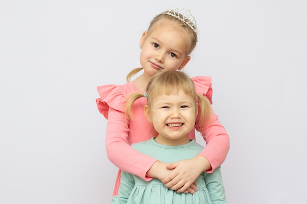 Two sisters hug each other , studio shot