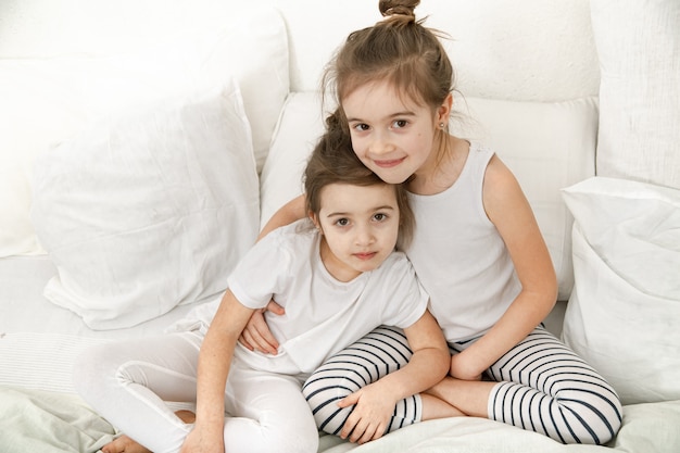 Photo two sisters hugging in pajamas before going to bed. the concept of family values and children's friendship close up.