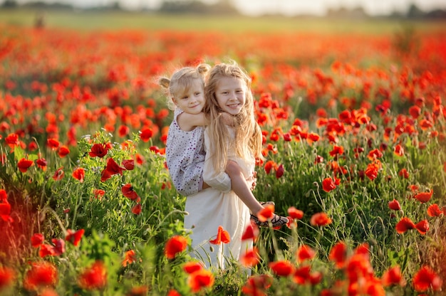 Due sorelle si concedono un campo di papaveri in estate