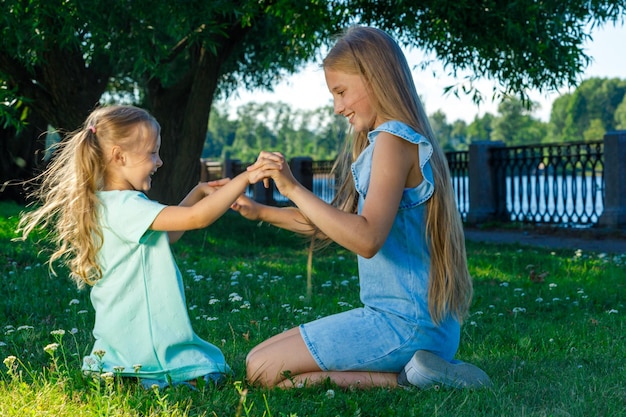 Two sisters playing together in the park on the grass