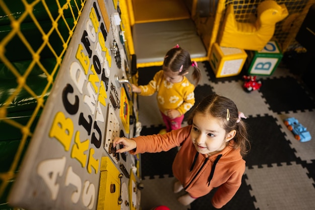 Two sisters playing with busy board at kids play center