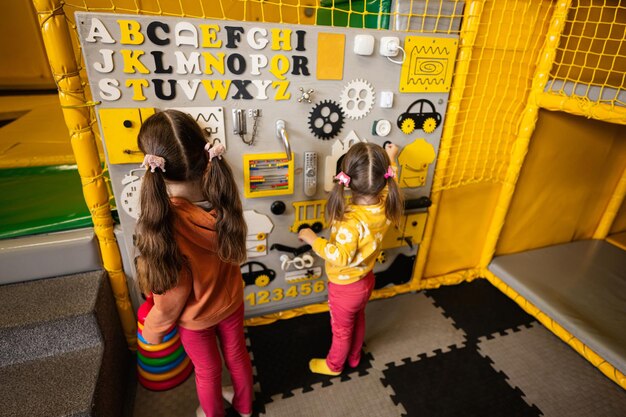 Two sisters playing with busy board at kids play center