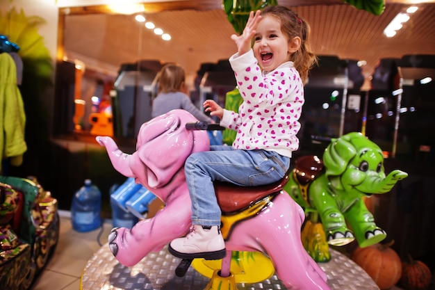 Two sisters rides an elephant carousel in fun children center