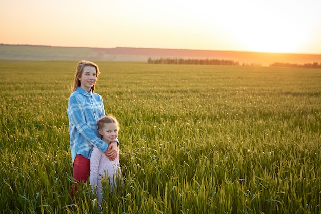 two sisters sit in the long grass at sunset, the girls play hide-and-seek