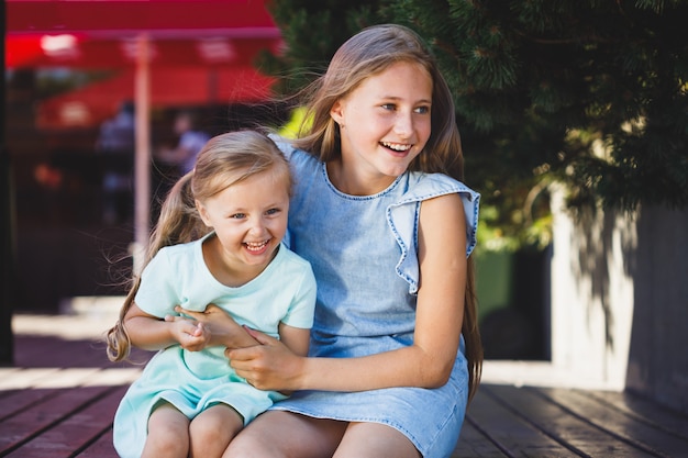 Two sisters sitting tickling each other and laughing