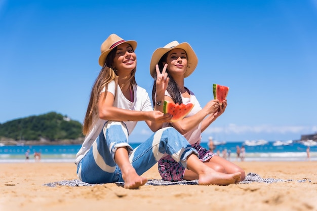 海を背景に休暇でスイカを食べるビーチで夏の2人の姉妹