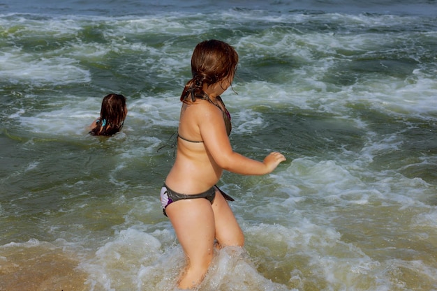 Photo two sisters swim in the ocean on waves