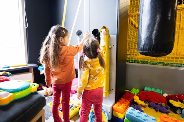 Two sisters throw balls inside tubes at kids play center