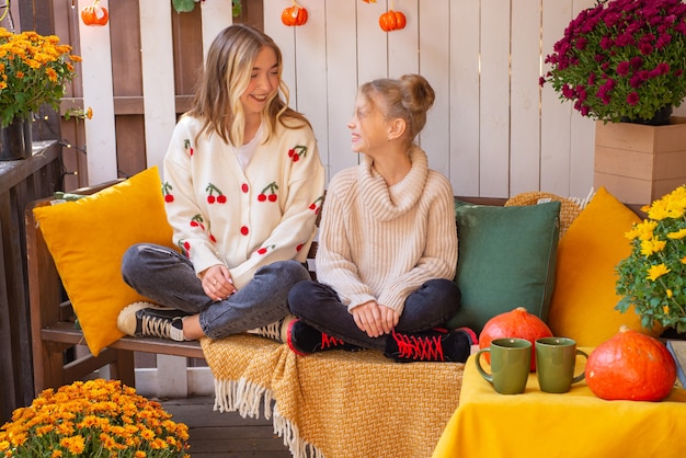 two sisters together in the fall celebrate and have fun on Halloween near the house family portrai