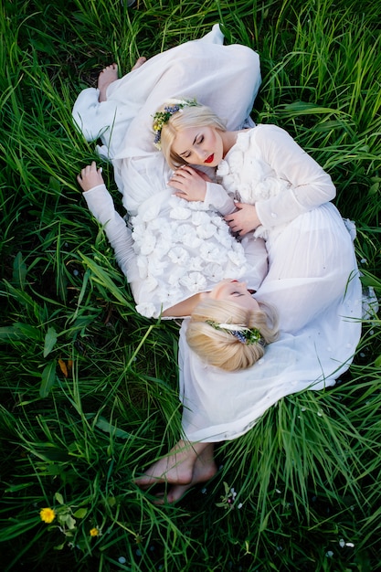 Two sisters twins lying on green grass